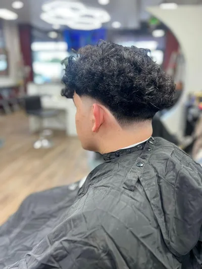 Corte con rizos y fade bajo, visto de lado